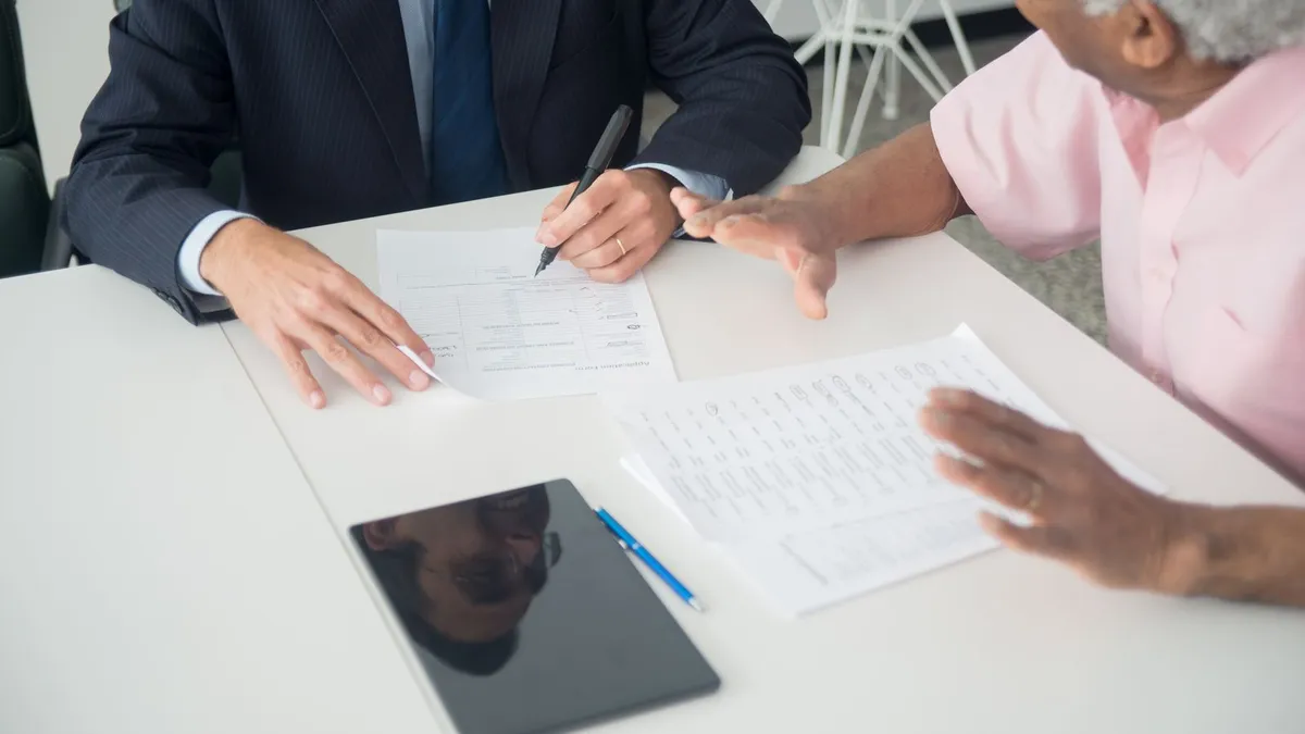 An insurance agent reviewing and signing an application with a senior client