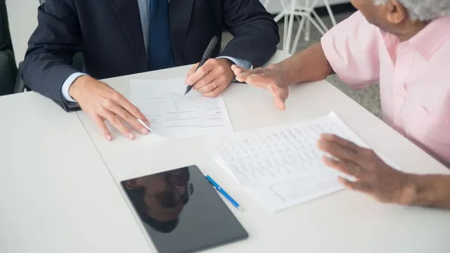 An insurance agent reviewing and signing an application with a senior client